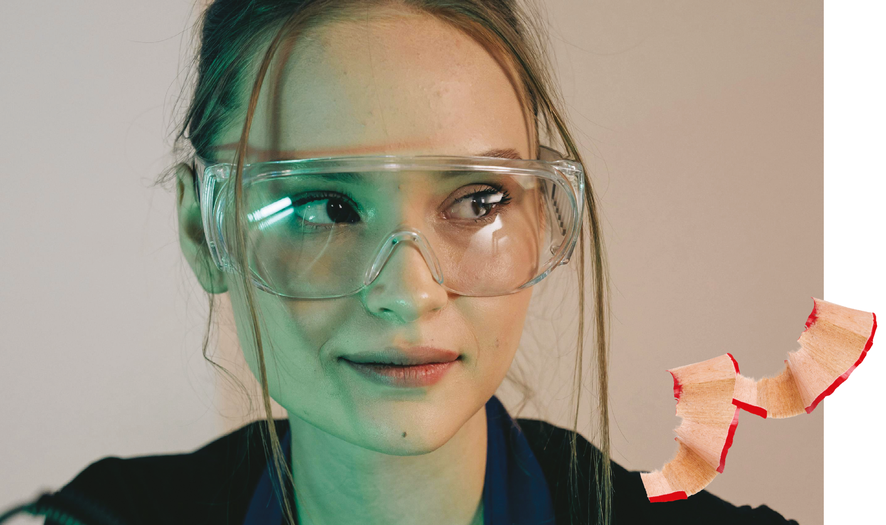 Eine junge Frau trägt Schutzbrille und blickt zur Seite, beleuchtet von grünlichem Licht, ergänzt durch eine Bleistiftspäne im Bild.